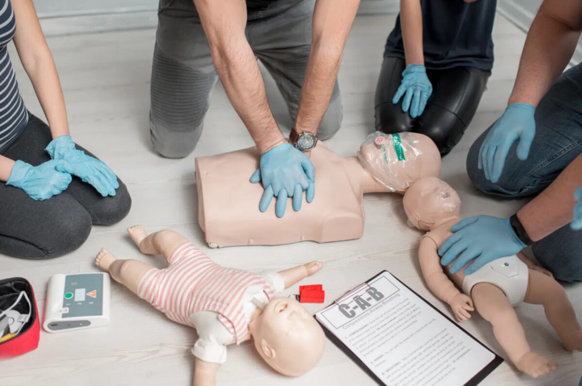 Marcela Brady teaching a CPR class with students practicing on manikins